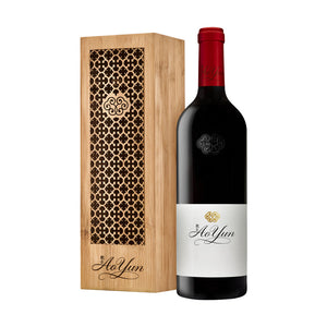 A bottle of Ao Yun wine from 2017, placed next to its bamboo gift box which has intricate cut-out patterns.