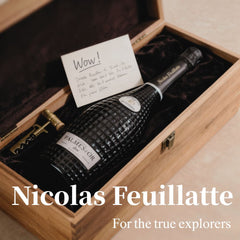 Nicolas Feuillatte champagne bottle in a wooden box with a card, on a beige surface.