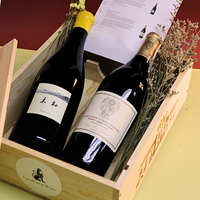Two bottles of wine in a wooden box with dried flowers.
