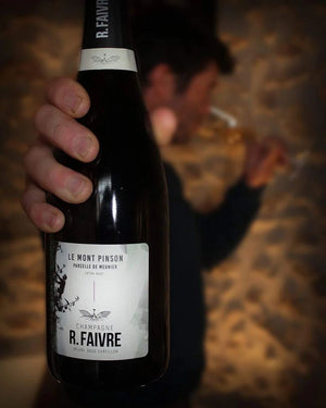 Bottle of R. Faivre champagne held by a hand with a blurred background