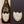 A wine bottle with a custom engraved label that reads 'Congrats! #teamwed.' The label is attached to the front of the bottle, which is placed against a wooden background.
